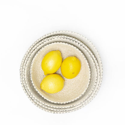 Three lemons in a woven basket on a white background