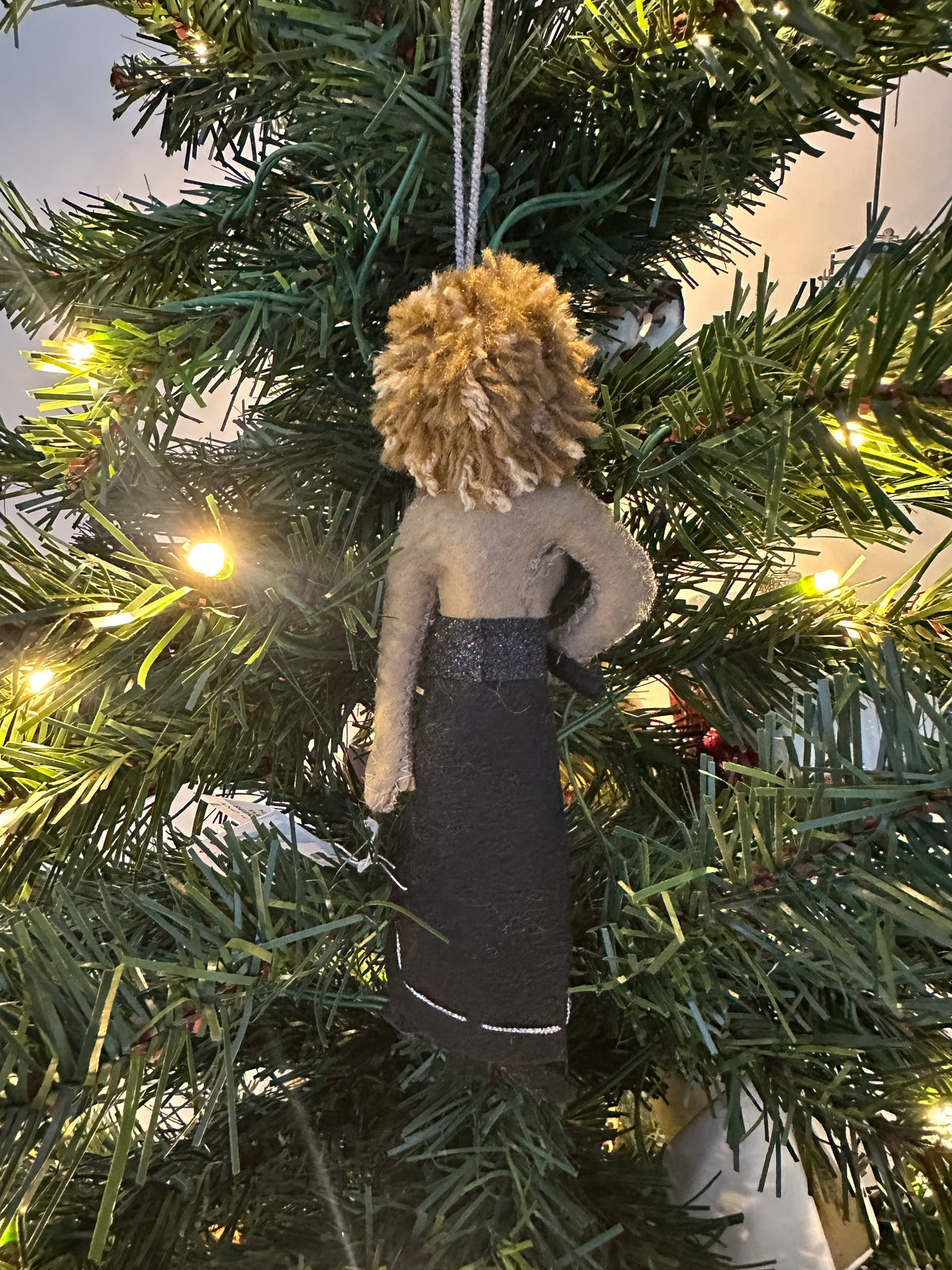 Decorative ornament hanging on a Christmas tree. Ornament is a female singer in a black dress holding a microphone.