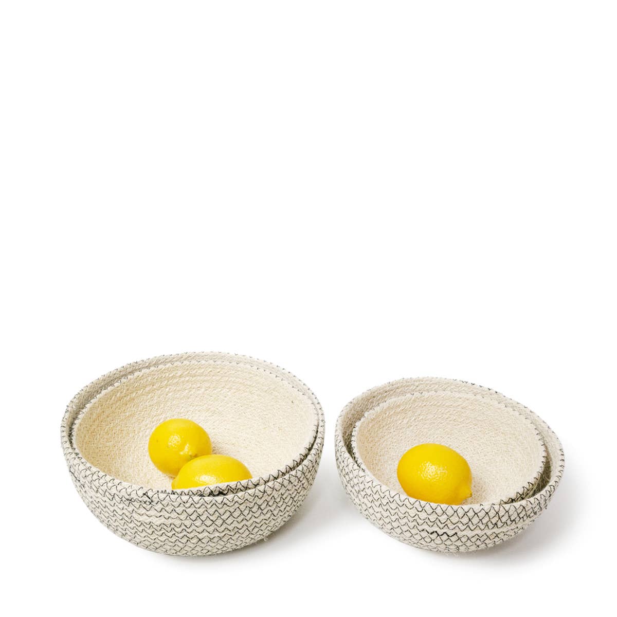 Two woven bowls, stacked, with lemons on a white background