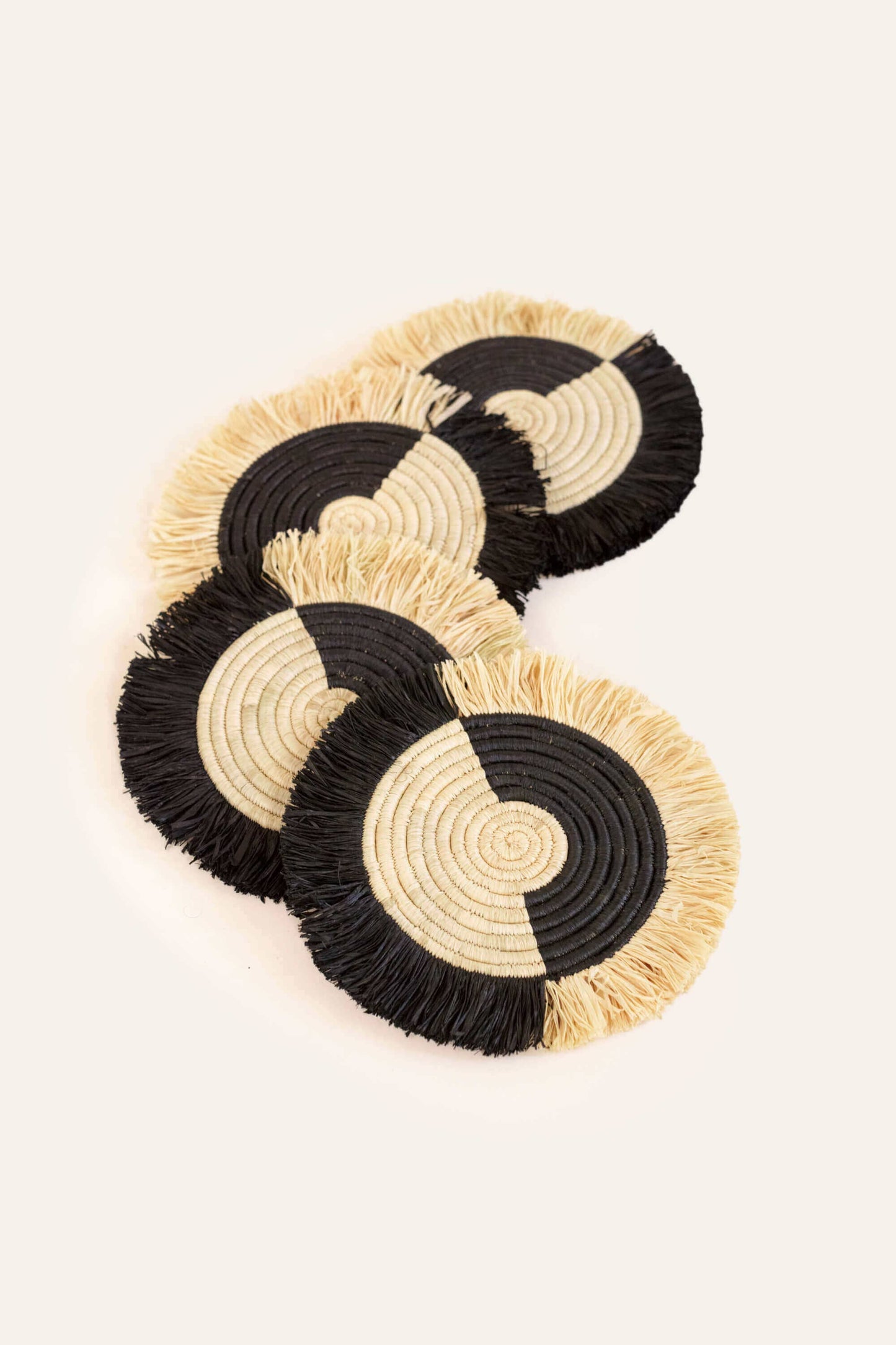 Set of four black and beige coasters on a light background