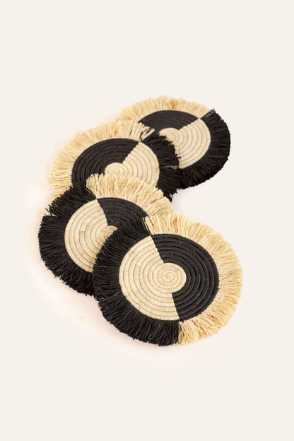 Set of four black and beige coasters on a light background