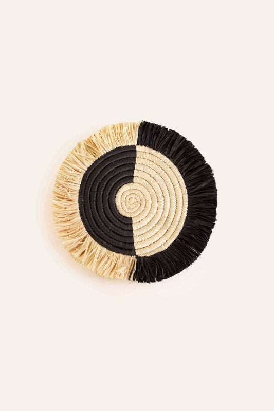 Round woven coaster with black and beige design on a white background