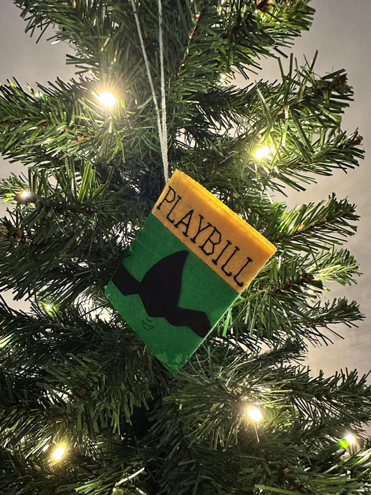 Playbill ornament hanging on a Christmas tree with lights.