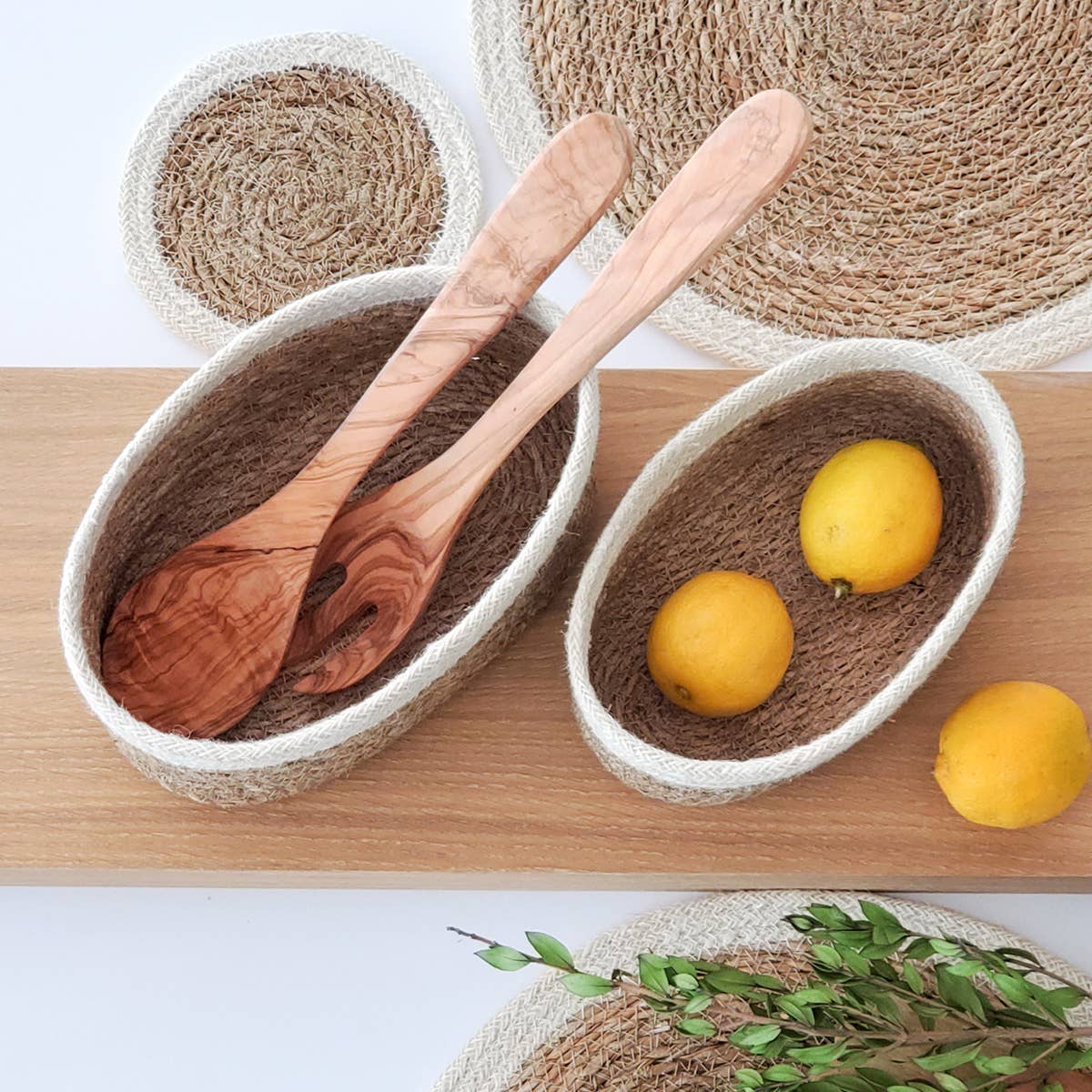 Wooden spoons in a woven bowl with lemons on a wooden surface