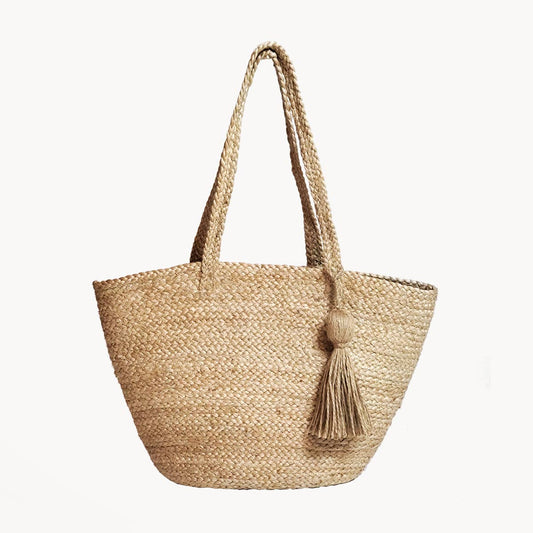 Woven straw tote bag with a tassel on a white background
