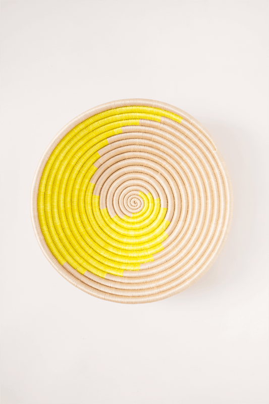 Woven basket with yellow and beige spiral pattern on a white background