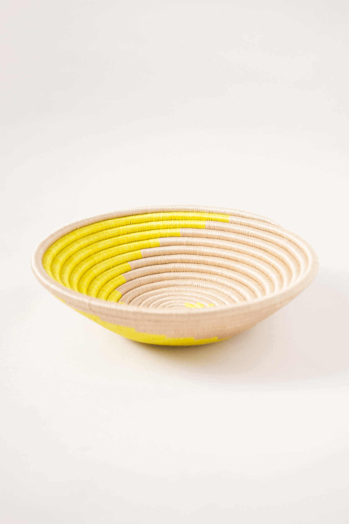 Woven bowl with yellow interior on a white background
